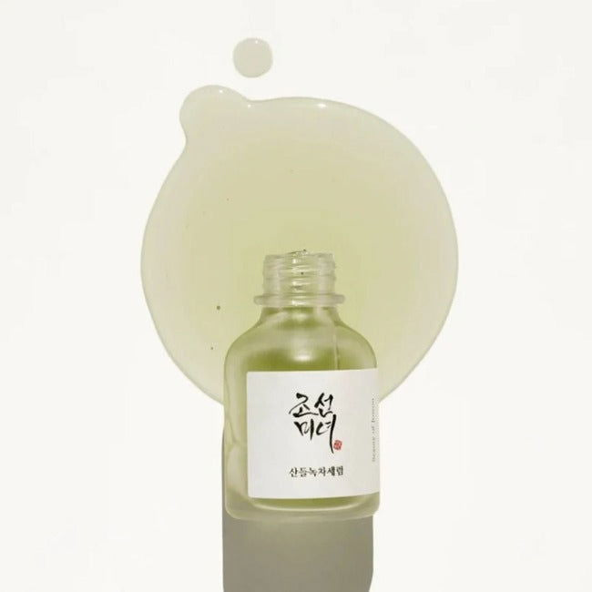 Bottle of skincare product with a droplet above it on a white background