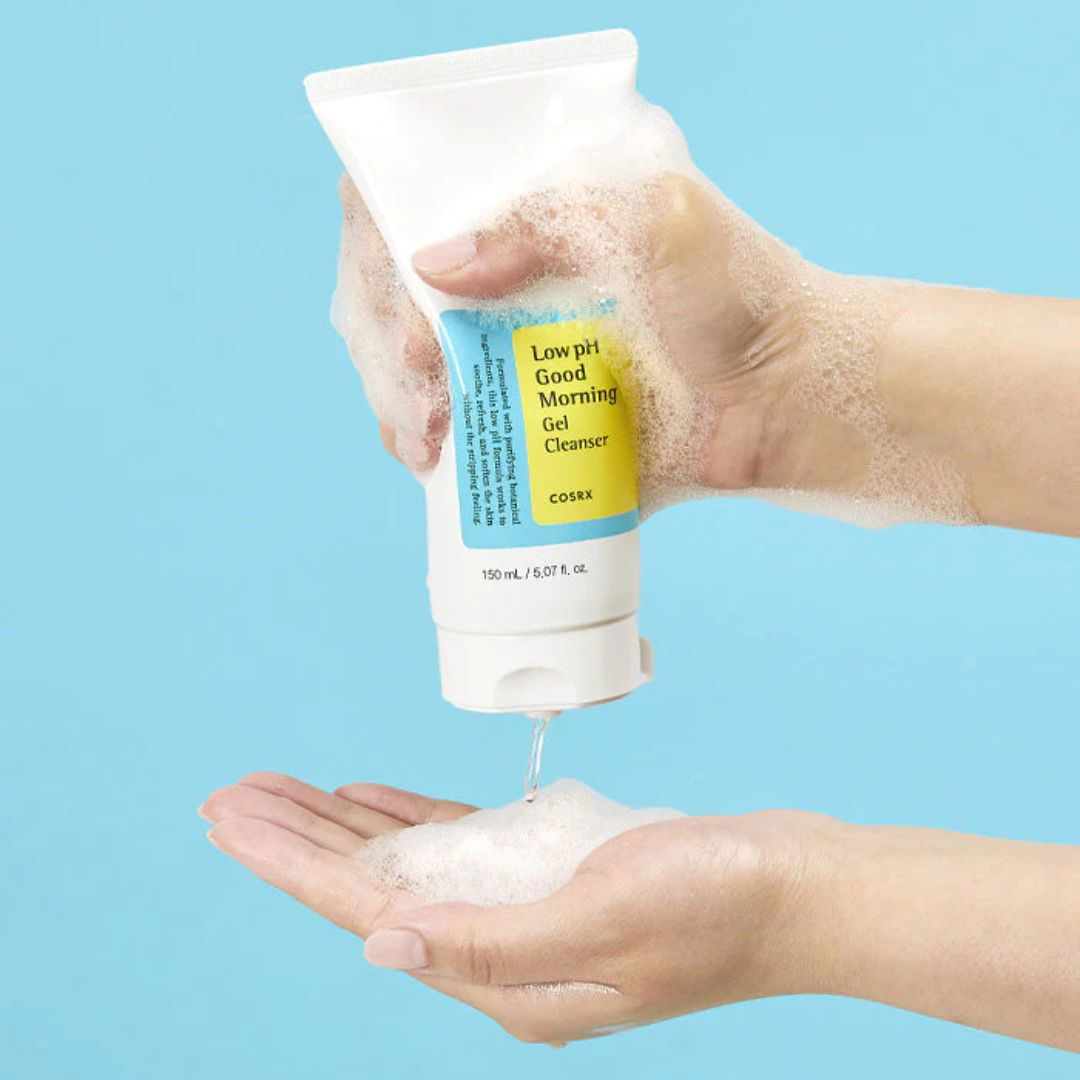 Hand holding a tube of COSRX Low pH Good Morning Gel Cleanser with foam