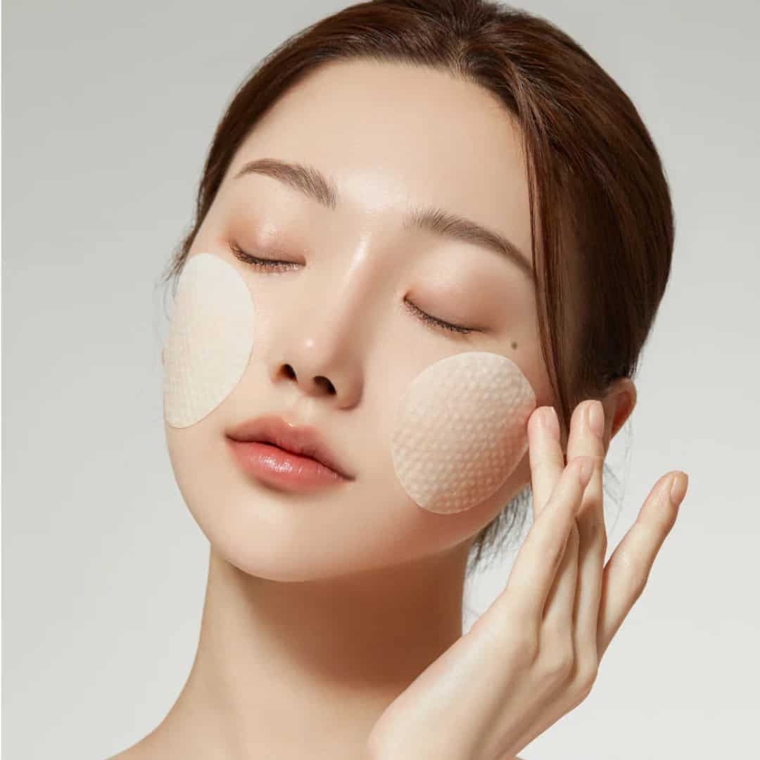 Woman applying MEDICUBE VITA C patches on face