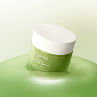 A green and white jar of TIRTIR matcha Calming Cream resting on a matching green surface against a soft light green background.